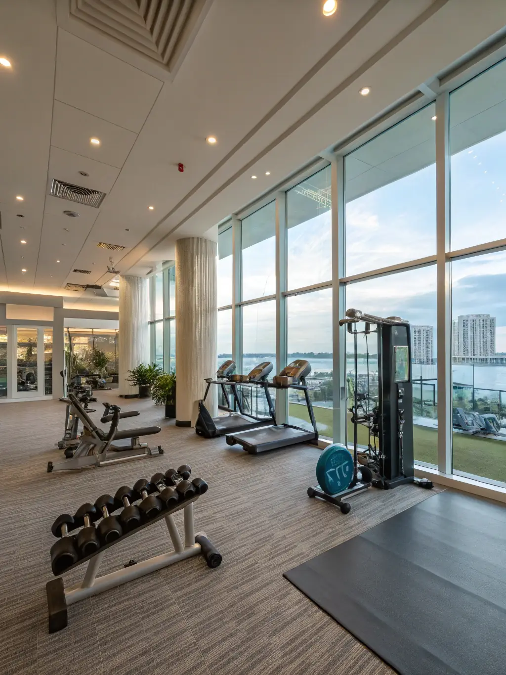 A brightly lit, modern photograph of the Springleaf Residence's state-of-the-art gym, equipped with treadmills, weights, and other fitness equipment. A personal trainer is assisting a resident.